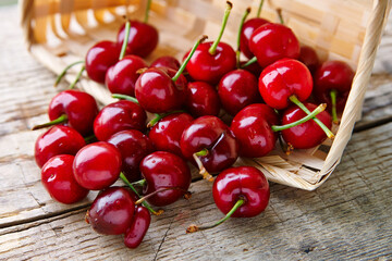 Cherry is scattered from the basket on a wooden table