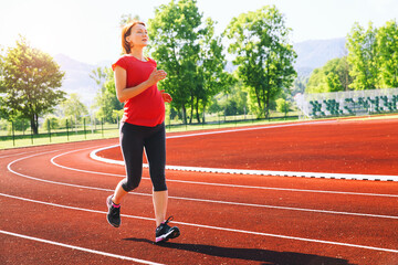 Fototapeta premium Pregnant woman jogging on running track in stadium.