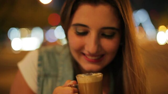 Teenage girl drinking coffee outdoors at night