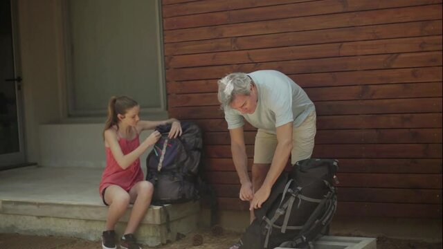 Father and daughter packing backpacks and embarking on trip