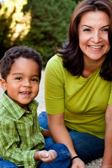 Hispanic woman smiling outside typing on a computer.