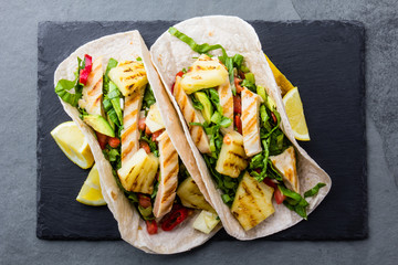 Mexican food. Tacos with grilled pineapple, chicken and vegetables, slate background
