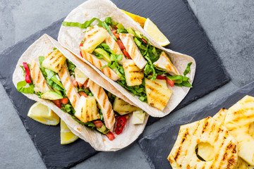 Mexican food. Tacos with grilled pineapple, chicken and vegetables, slate background