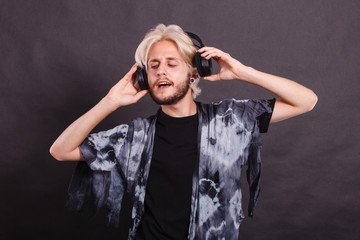 Blonde man singing in studio wearing headphones