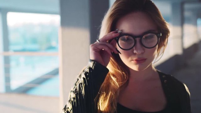 Cute young blonde girl in eyeglasses turns to camera and corrects it. Attractive nerdy girl. Being positive, cheerful mood. Natural beauty.
