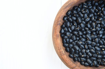black beans in wooden bowl isolated on white background