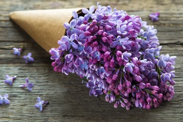 Photo sur Plexiglas Lilas Bouquet de fleurs lilas dans un cornet en papier craft sur le vieux fond en bois