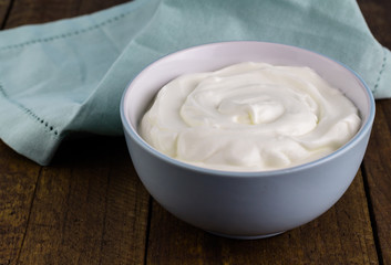 Natural creamy swirled yoghurt in bowl close up - Background with Greek yogurt and space for text