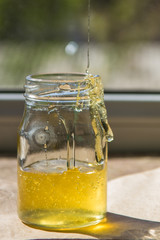 Organic pure honey in jar on window sill. Stream of honey
