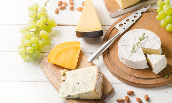 Different kinds of cheeses on a white wooden table