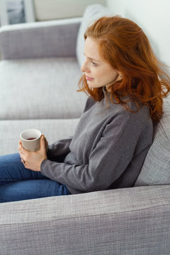 frau sitzt auf dem sofa und entspannt mit einer tasse tee
