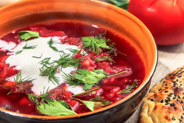 beet soup in a clay plate served on a rustic table