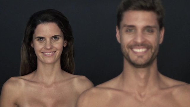Couple with bare shoulders smiling cheerfully, focus shifting from one to the other