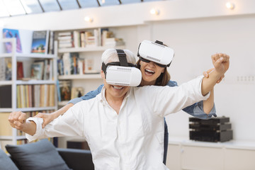 Mature couple using virtual reality headset in living room