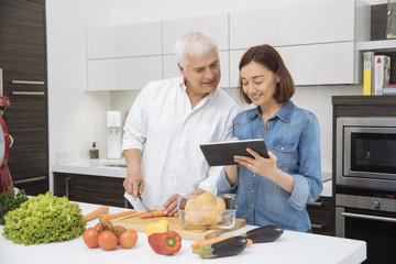 Mature couple cooking meal at home