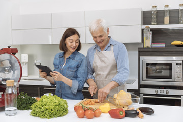 Mature couple cooking meal at home