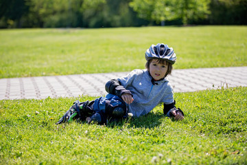 Cute little child, boy, riding on a rollerblades in the park