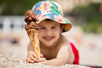Sweet little child, boy, eating ice cream on the beach