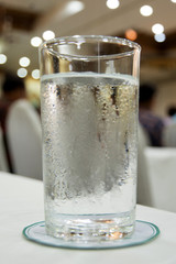 glass of water on wooden table bokeh background