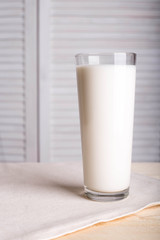 A glass of milk on a linen napkin on a wooden table on a white background. Place for inscription or text. Side view.