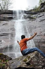 Young man looking at the waterfall in jungles. Man enjoy in wonderful nature in spring