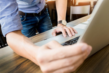 Attractive  man in casual business sitting at a table working on his laptop computer at home office in front of a window