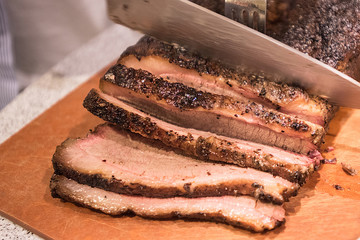 Barbecue beef brisket being cut on cutting board