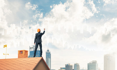 Man architect draw silhouette of modern city on blue sky. Mixed 