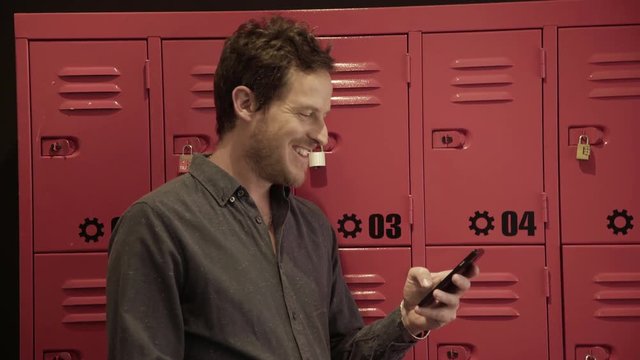 Man standing in front of lockers using smart phone