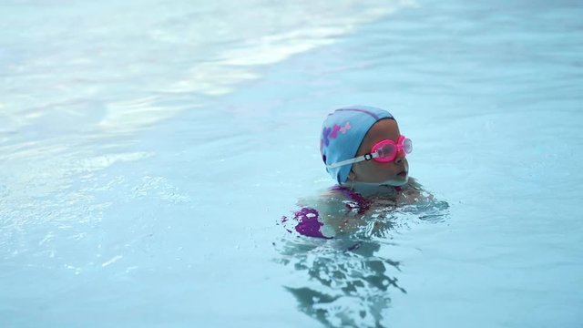 Cute girl training butterfly in swimming pool. Concept of sport, health and childhood. 
