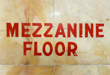 Red mezzanine floor sign written on marble wall