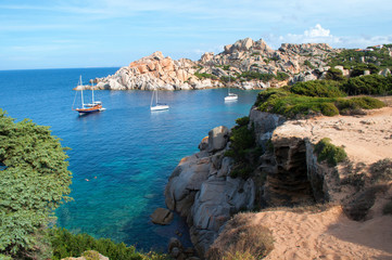 Fototapeta na wymiar Boats moored in a bay on the clear sea around the rocks in the Capo d'Orso area of the island of Sardinia.