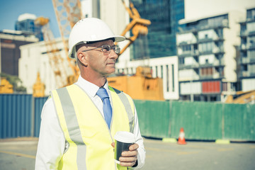 Engineer builder on construction site at sunny day with coffee i