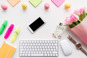 Top view of smartphone, keyboard with computer mouse, bouquet of pink tulips and office supplies isolated on white