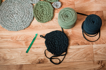 Knitted yarn in large spools. Black and green, olive yarn on a wooden background