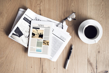 Newspaper with tablet on wooden table