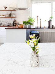 spring flowers at the table with kitchen unfocused in the background