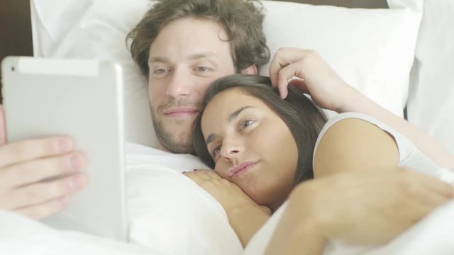Couple using digital tablet in bed