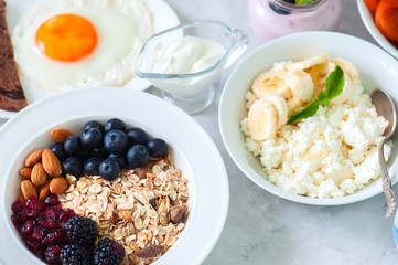 Healthy breakfast concept. Homemade granola with blackberry, dry cranberry, blueberry, almond, yogurt in a jar, sour cream and milk on a wooden background. Close up and copy space.