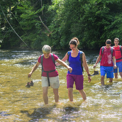 Wanderer waten durch einen kleinen Fluss