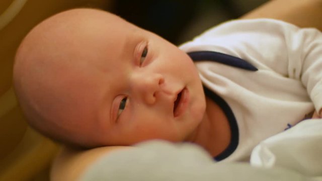 Young mother holds a sleeping baby in her arms and gently caresses his face. Mom takes care of the baby. The concept of family well-being, love and tranquility. Mother and newborn in maternity home