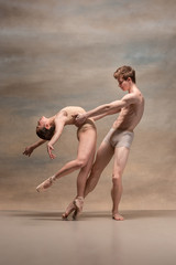 Couple of ballet dancers posing over gray background