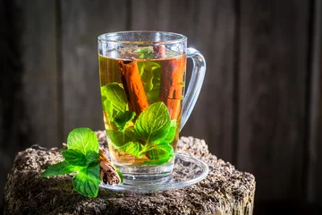 Photo sur Plexiglas Theé Hot tea with cinnamon bark and green leaves