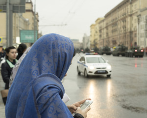 Profile of a girl with a smartphone outdoors on a rainy day.
