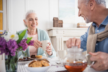 smiling grey haired couple having breakfast at home