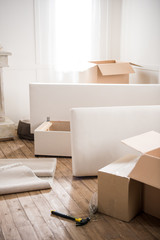 Cardboard boxes, furniture and hammer with nails in empty room, relocation concept