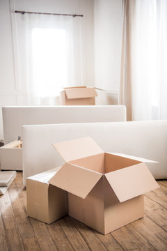 Close-up view of cardboard boxes and furniture in empty room, relocation concept