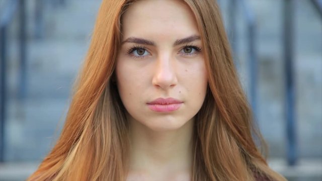 Portrait of beautiful angry sad young girl with long red hair. Slow motion