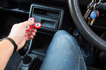 Close-up of a man's hand playing with a spinner while in a traffic jam on the background of the...