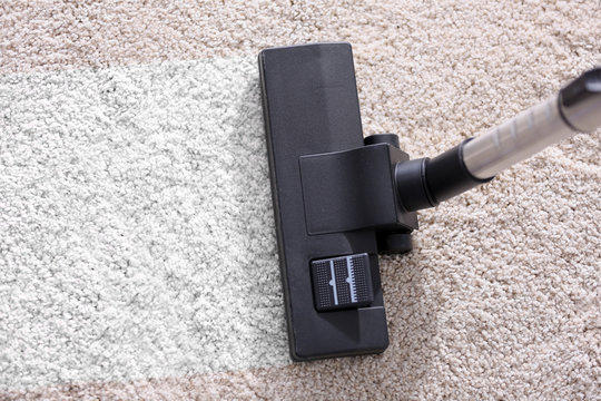Vacuum cleaner sweeping a white carpet, close up